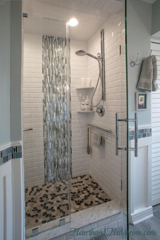 Glass Accent Mimics a Waterfall Cascading onto the Pebble Shower Floor